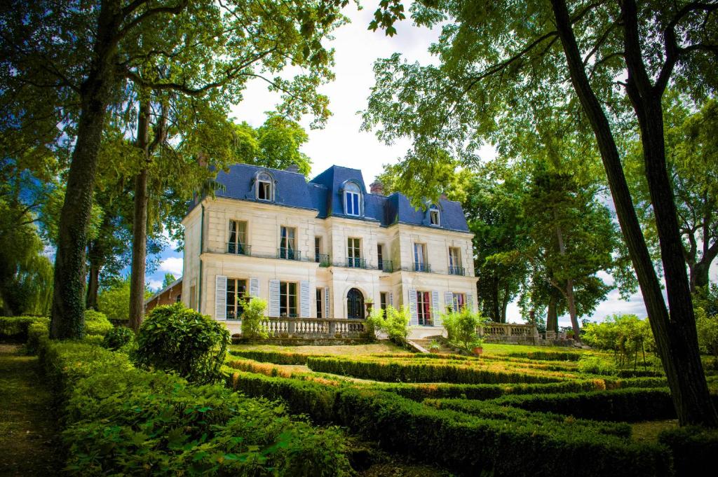 une grande maison blanche avec un toit bleu dans l'établissement Château de Picheny - B&B Esprit de France, à Picheny