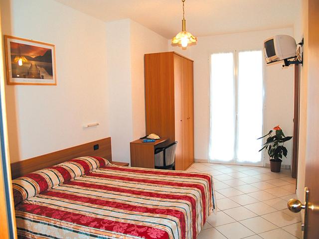 a bedroom with a bed with a striped blanket at Hotel Adriana in Laigueglia