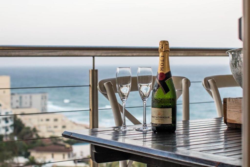 a bottle of champagne and two wine glasses on a table at 515 Umdloti Resort in Umdloti