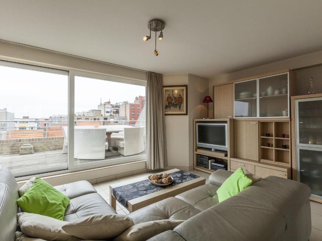 a living room with a couch and a large window at Penthouse with 2 terraces and sea casino views in Middelkerke