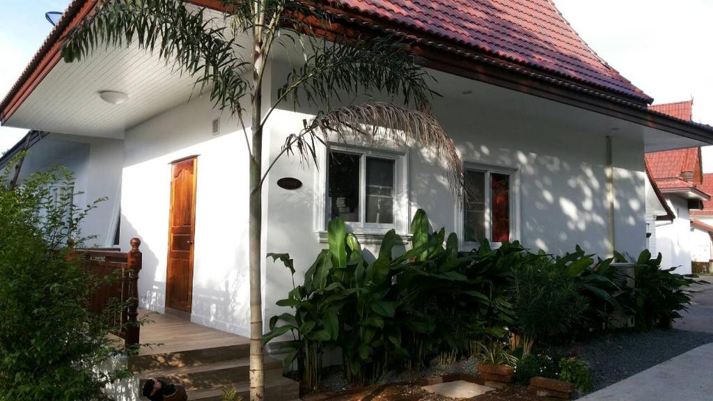 a white house with a palm tree in front of it at Hibiscus Cottage in Ban Dan Kao