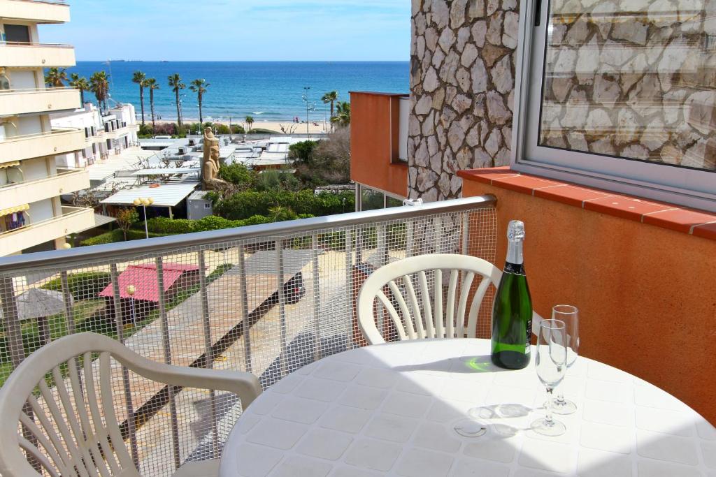 a table with a bottle and two glasses on a balcony at Dms Planet Costa Dorada in La Pineda