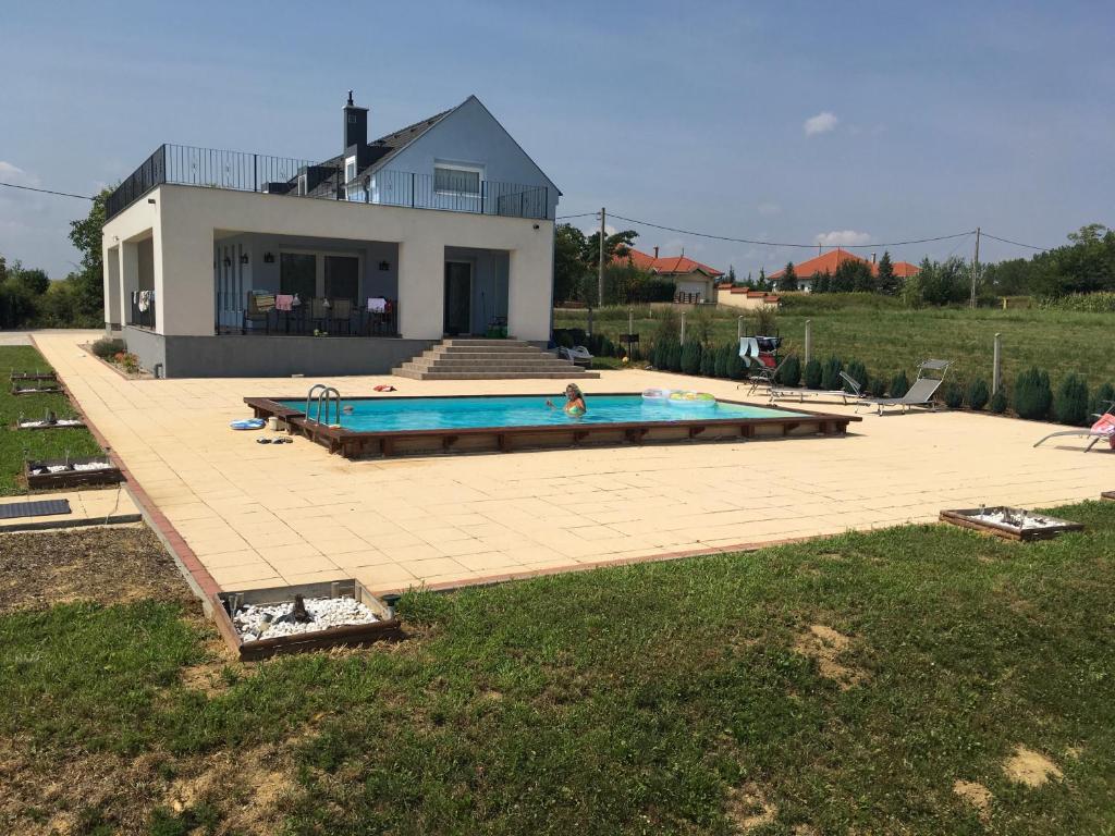 uma casa com piscina em frente a uma casa em Balatonview - villa Myriam em Nemesbükk