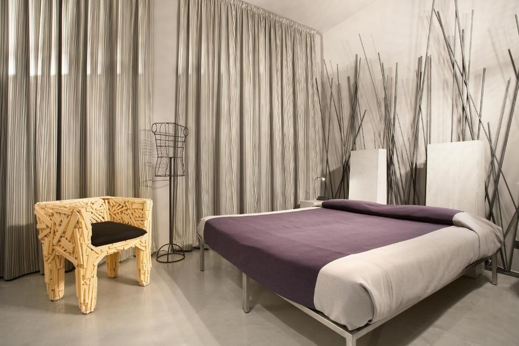 een slaapkamer met een bed, een stoel en gordijnen bij Art Hotel Boston in Turijn