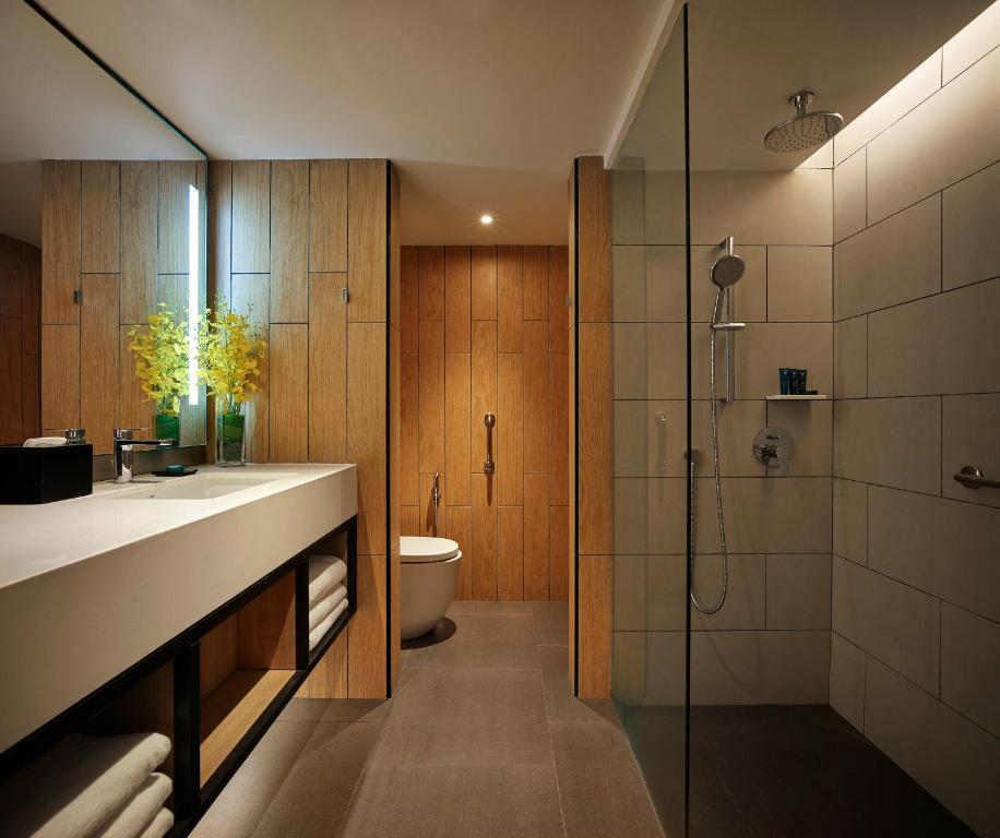 a bathroom with a shower and a sink and a toilet at PARKROYAL Penang Resort in Batu Ferringhi