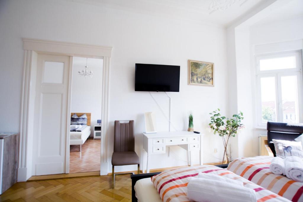 een witte woonkamer met een bed en een bureau bij Auwald Apartment in Leipzig