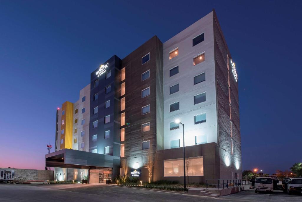 un edificio illuminato con un parcheggio di fronte di Microtel Inn & Suites by Wyndham San Luis Potosi a San Luis Potosí