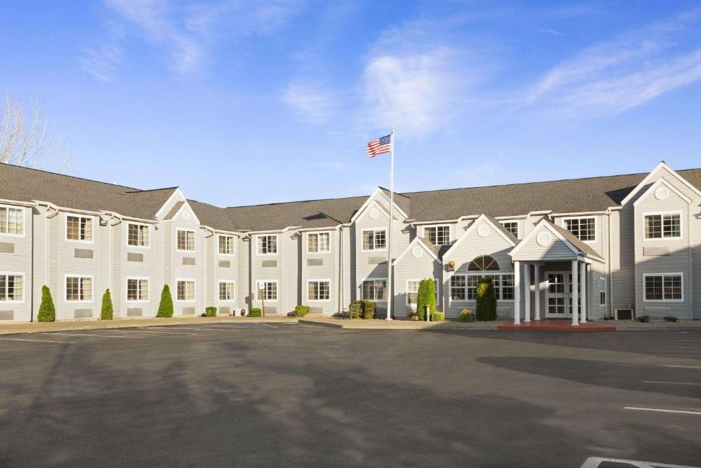 a large white building with an american flag at Microtel Inn by Wyndham - Albany Airport in Latham