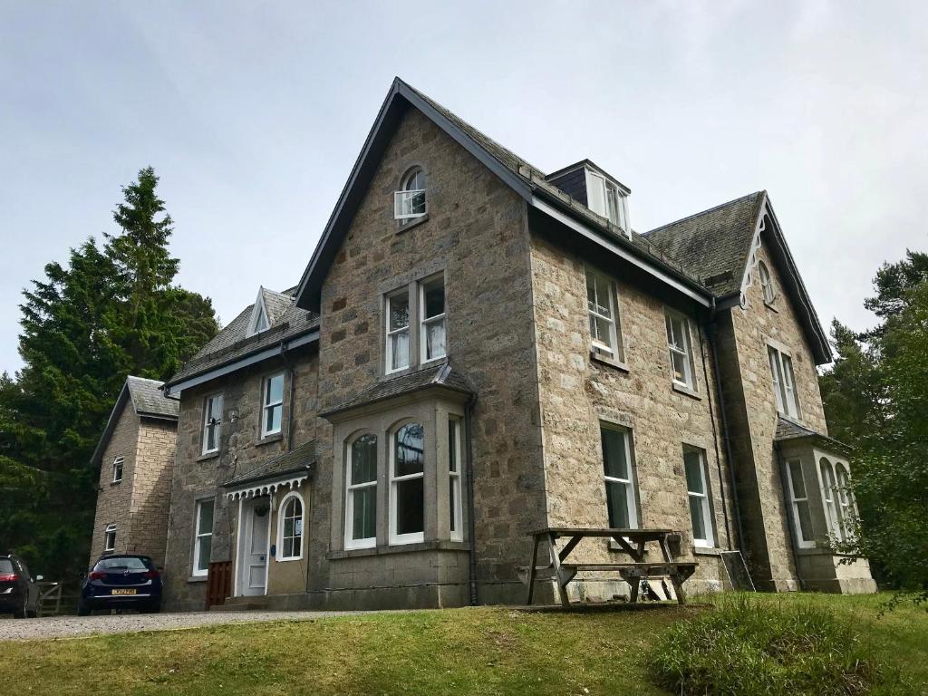 un gran edificio de piedra con un banco delante en Braemar Youth Hostel, en Braemar