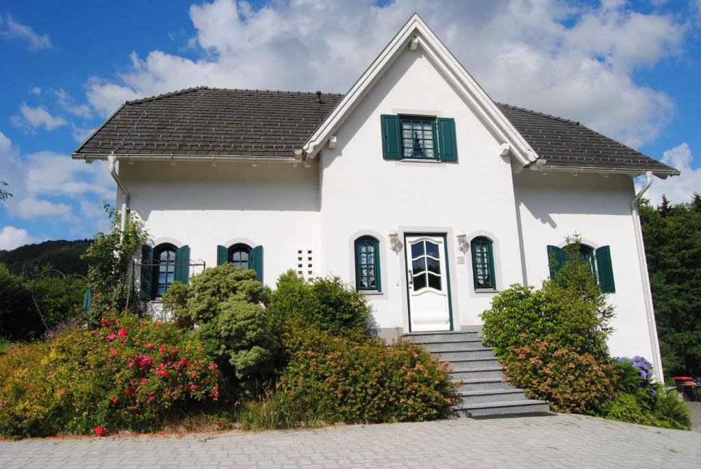 uma casa branca com persianas verdes e flores em Bed and Breakfast Petra Huber em Vichtenstein