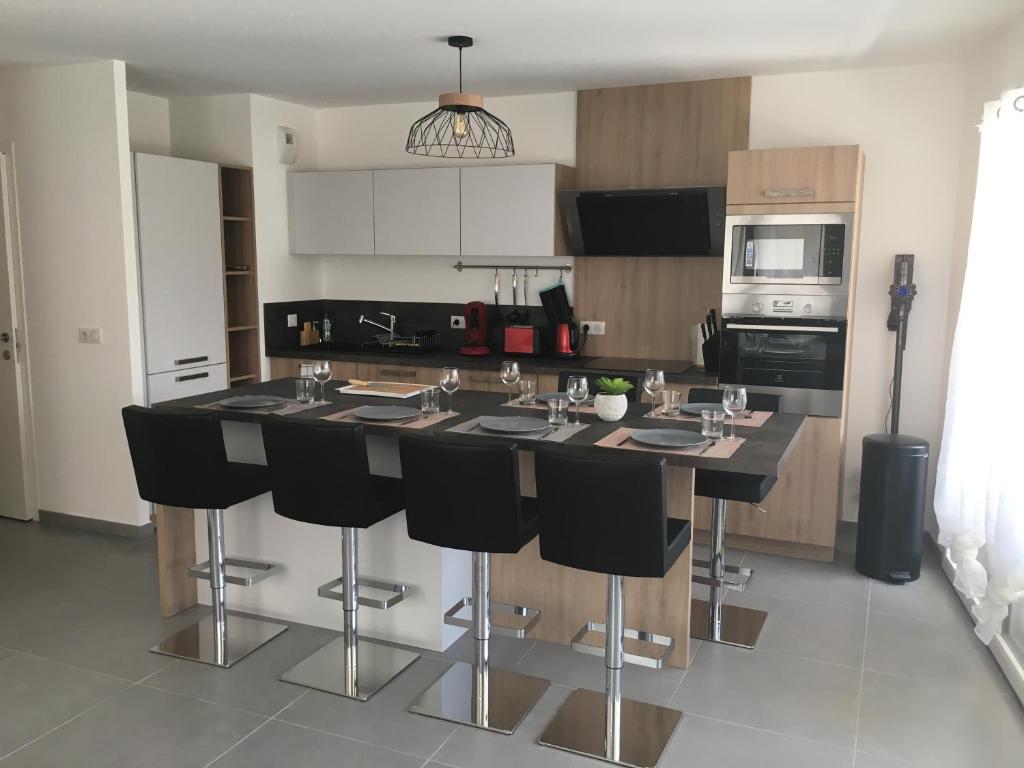 a kitchen with a large island with black bar stools at Relax In in Annecy