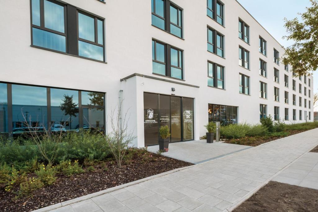 an office building with glass windows and a sidewalk at Super 8 by Wyndham Munich City North in Munich