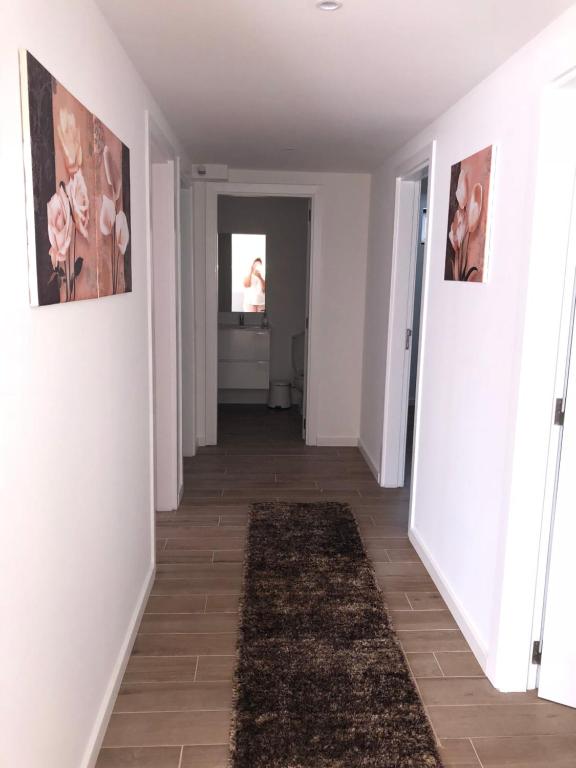 um corredor com paredes brancas e um tapete em alojamento Xa andar em Nazaré