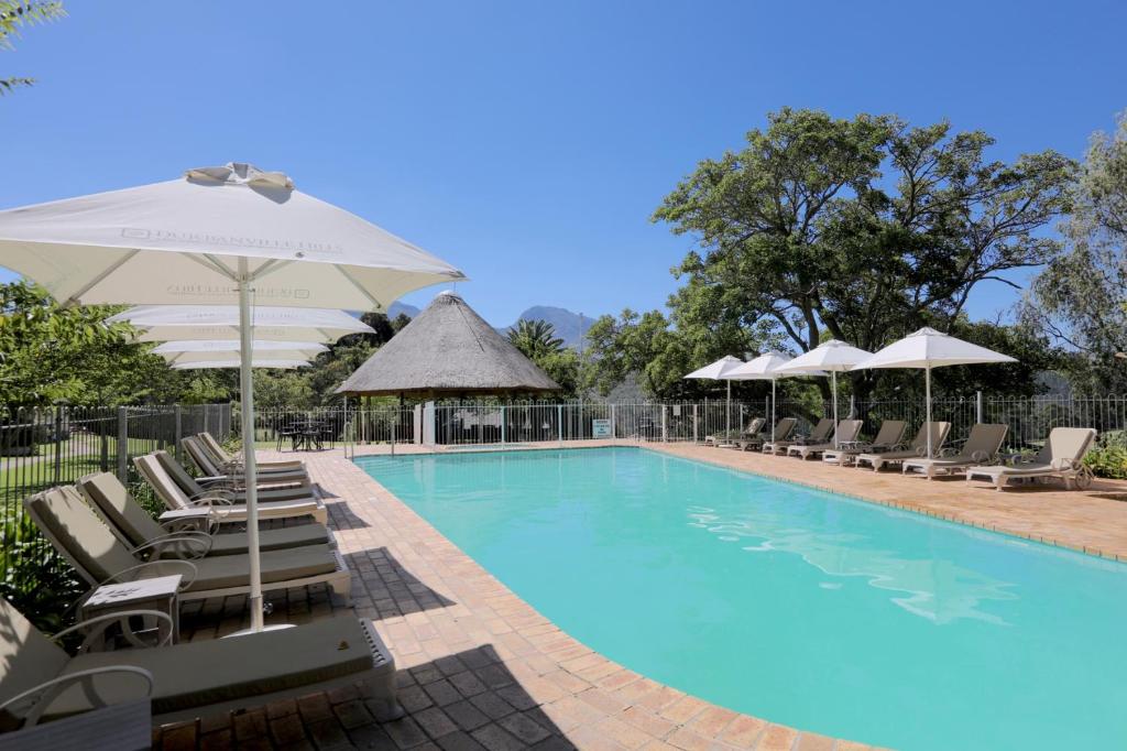 a swimming pool with chairs and umbrellas at Eight Bells Mountain Inn in Ruiterbos