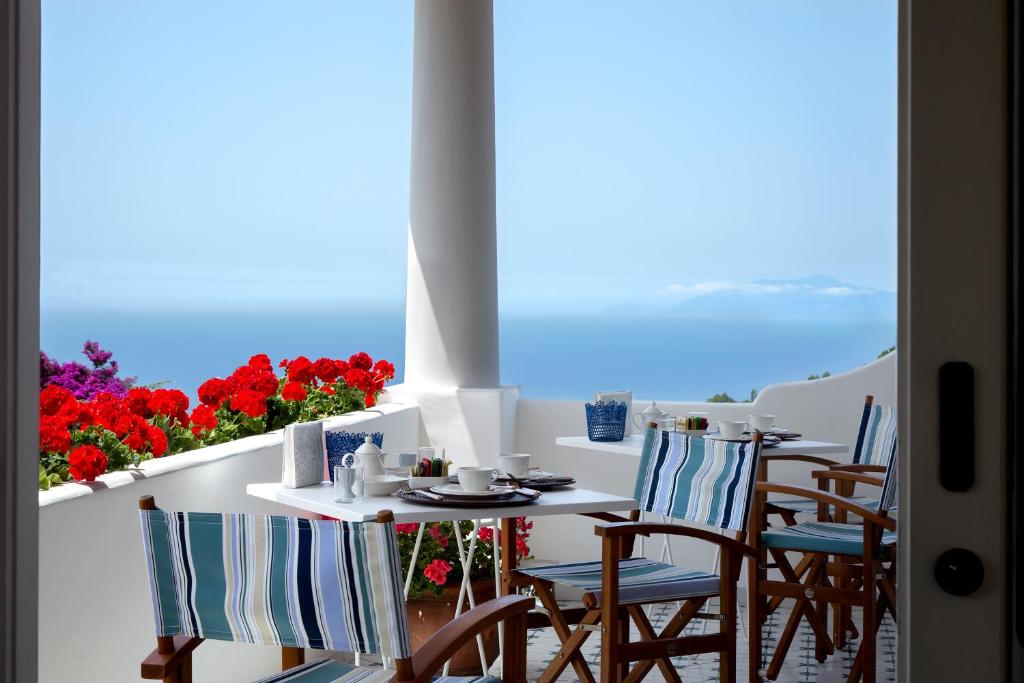 een tafel en stoelen op een balkon met bloemen bij Riolinciano14 B&B in Anacapri