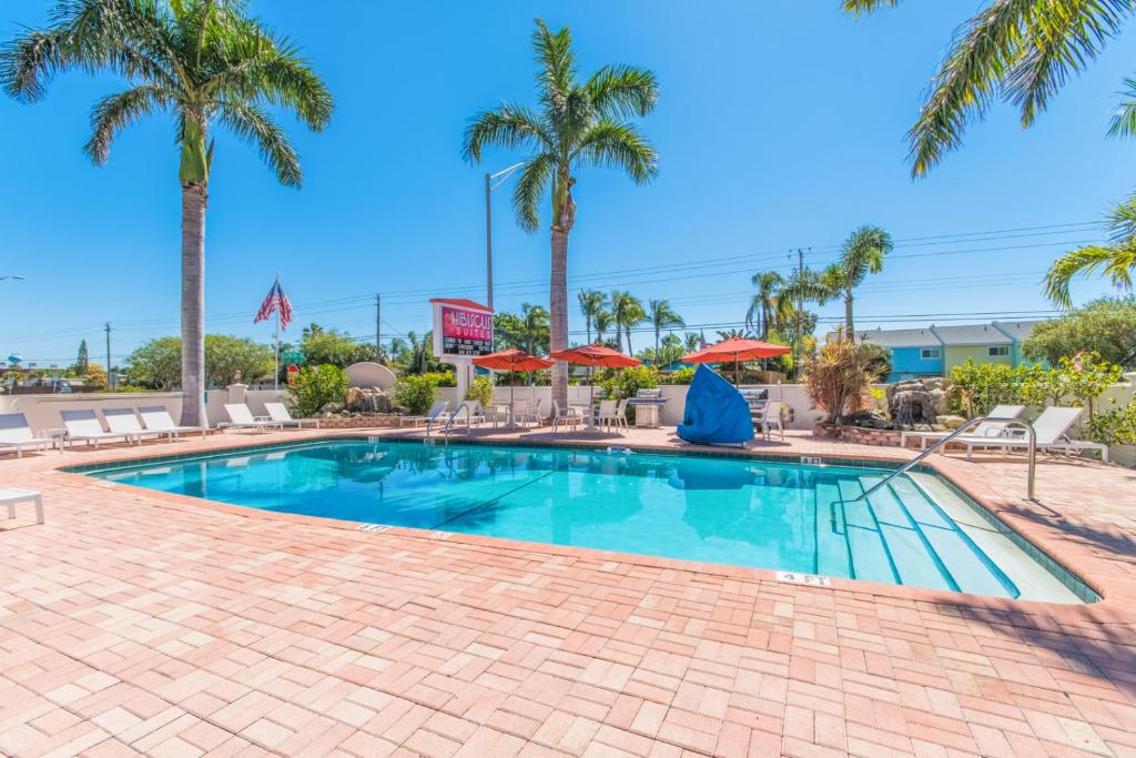 uma piscina com palmeiras e guarda-sóis em Hibiscus Suites - Sarasota em Sarasota