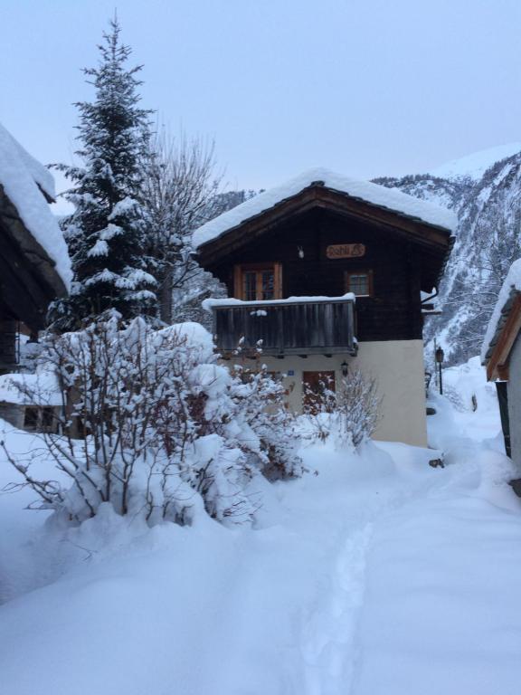 una casa cubierta de nieve con un árbol en el fondo en Rehli en Blatten bei Naters