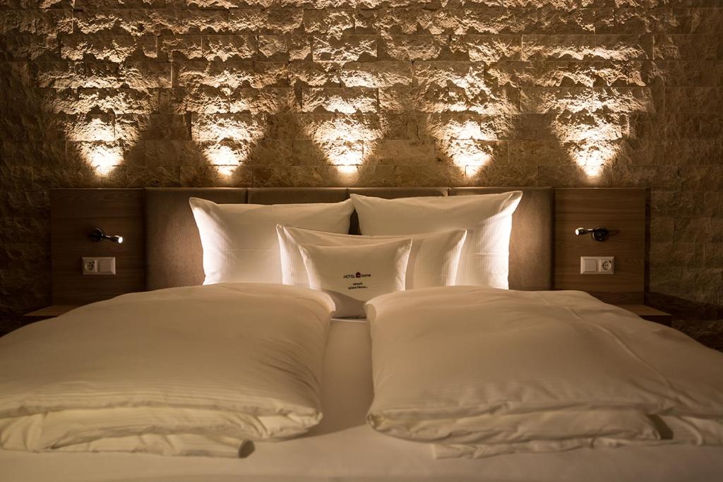 ein Bett mit weißen Kissen und eine Wand mit Licht in der Unterkunft Hotelmyhome in Hornberg