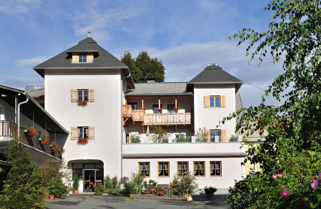 ein weißes Gebäude mit schwarzem Dach in der Unterkunft Mitschighof - Apartments und Pension - Heidis-Welt, Mitschig in Hermagor