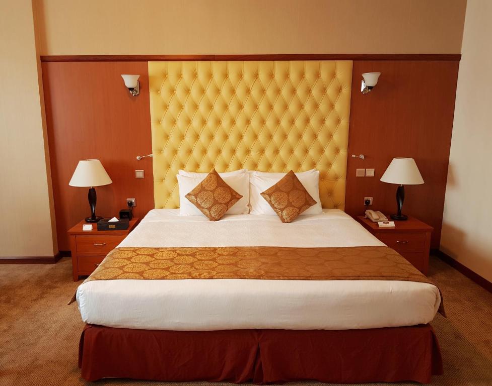 a bedroom with a large bed with a yellow headboard at THE PARK HOTEL Formerly Al Jawhara Gardens in Dubai