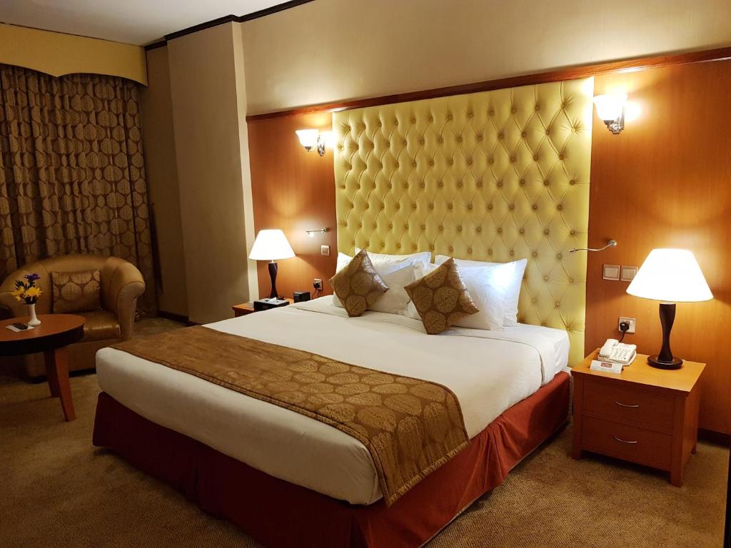 a hotel room with a large bed and a chair at THE PARK HOTEL Formerly Al Jawhara Gardens in Dubai