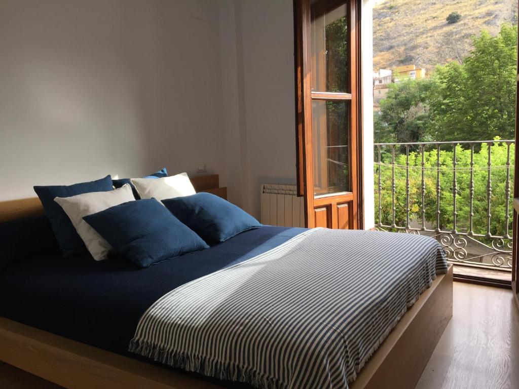 Cama en habitación con ventana grande en Apartamentos Viejo Continente, en Cuenca