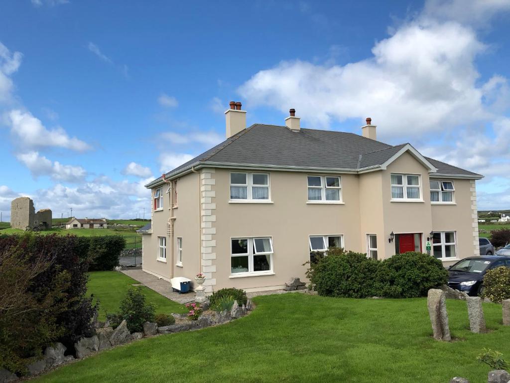 une grande maison blanche avec une cour dans l'établissement Moloney House, à Doolin