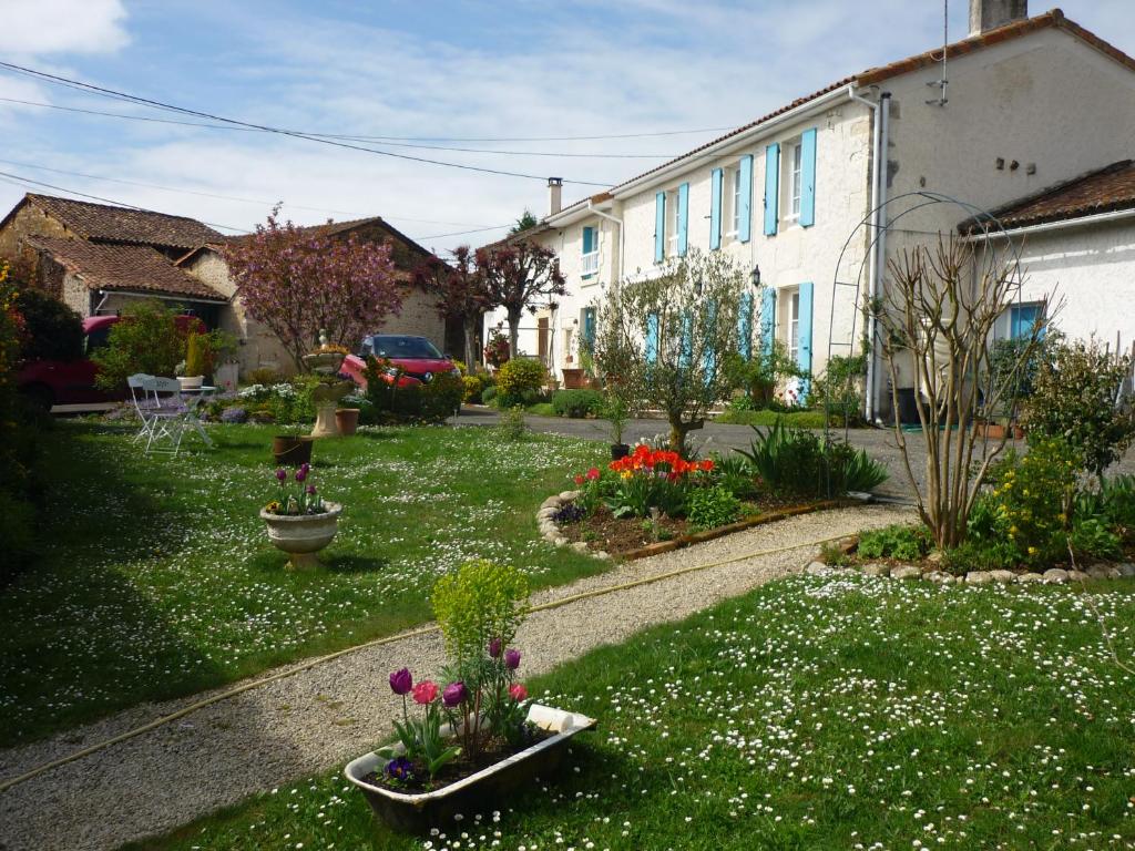 un giardino fiorito in un cortile con una casa di Les Hirondelles Du Paradis 6 rue des Oiseaux a Beaulieu-sur-Sonnette