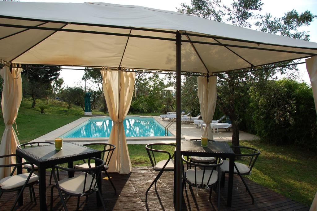 un patio con tavoli e sedie sotto un baldacchino accanto alla piscina di Tenuta Merlano a Sacrofano