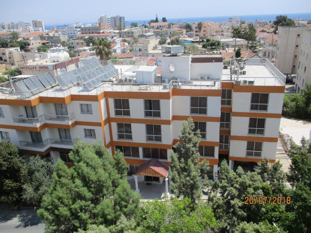 un edificio de apartamentos con árboles en el primer plano en Onisillos Hotel en Lárnaca