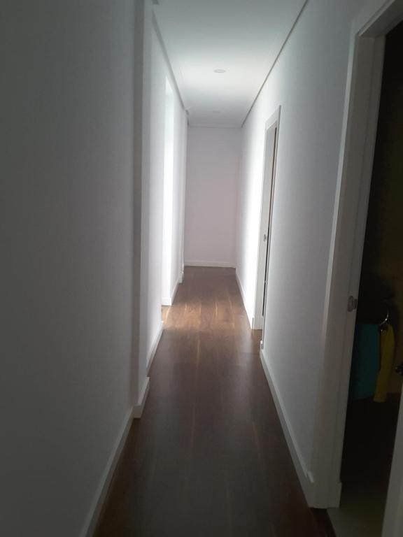 un couloir vide avec des murs blancs et du parquet dans l'établissement Alojamiento Cádiz, à Cadix
