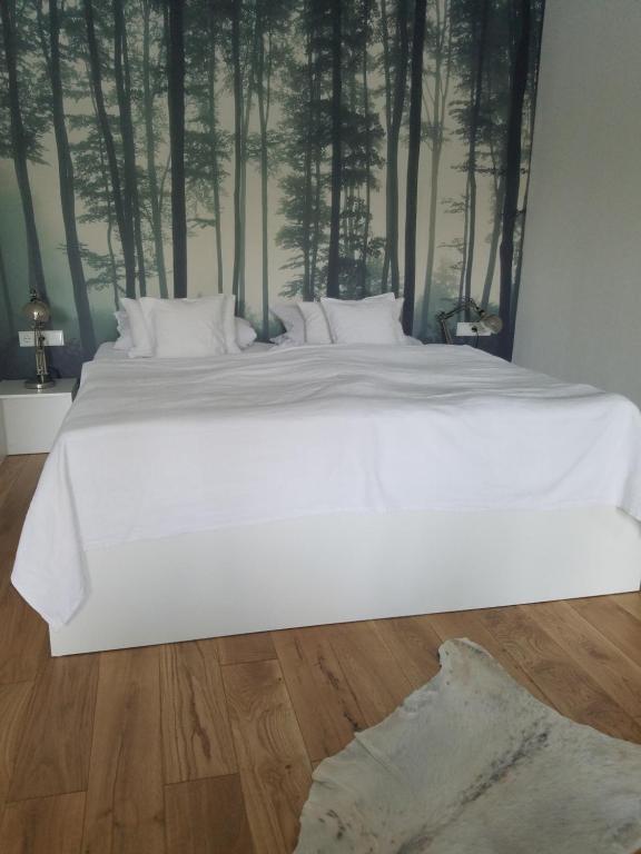 a large white bed in a bedroom with trees on the wall at Webergarten in Oestrich-Winkel
