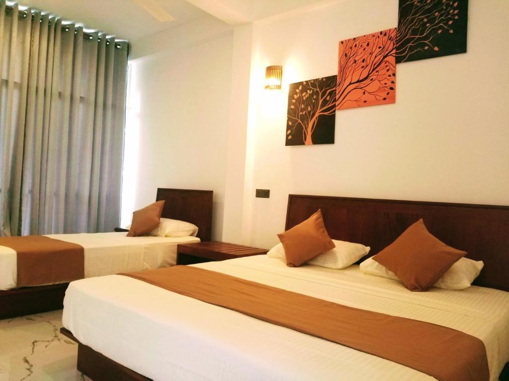 Cette chambre comprend 2 lits et une fenêtre. dans l'établissement Queens mount, à Kandy