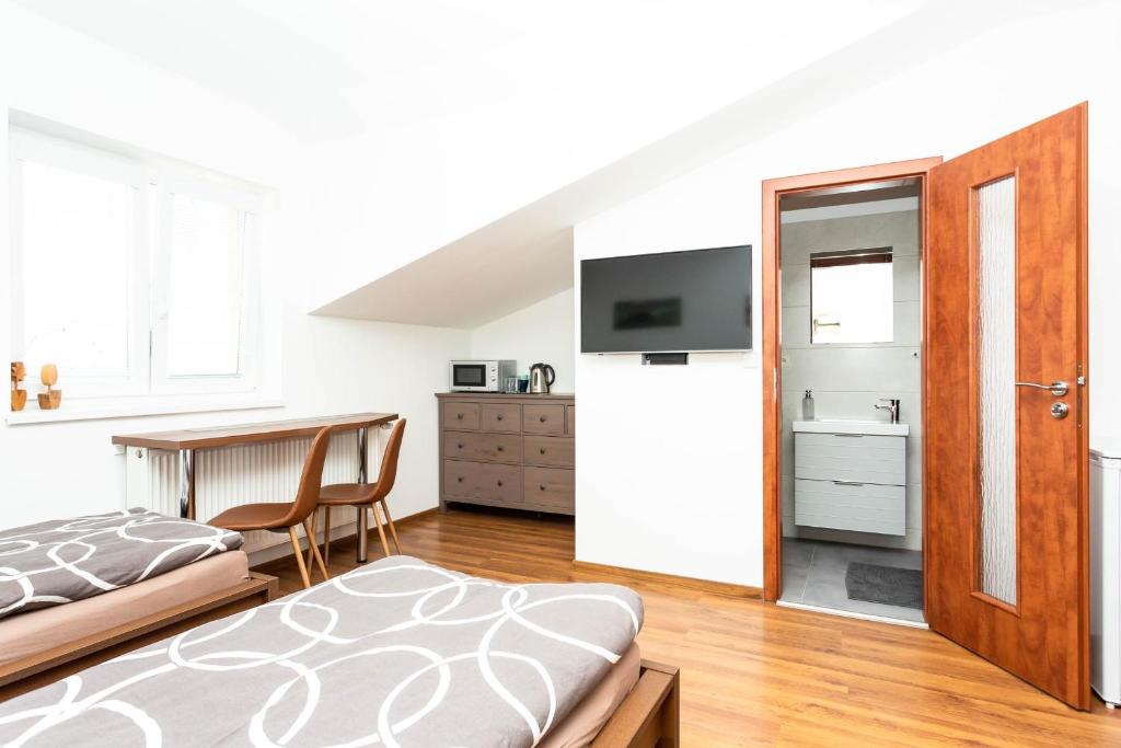 a bedroom with a bed and a refrigerator and a tv at Pohoda Ubytovanie Stupava in Stupava