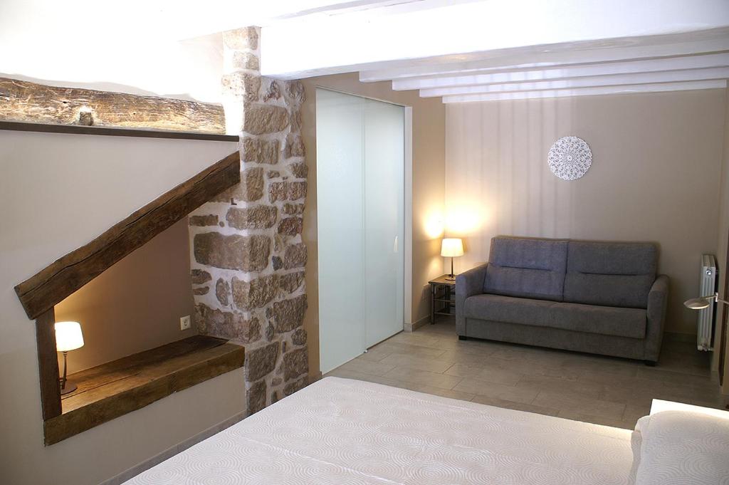 sala de estar con sofá y pared de piedra en Habitacions Plaça Major en Santa Pau