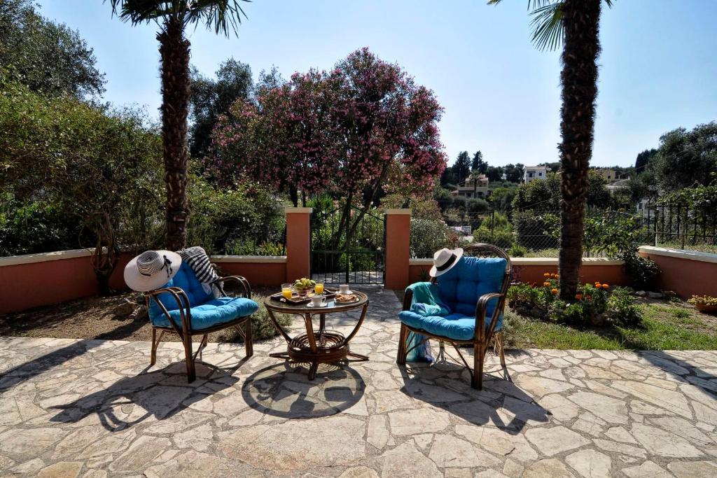 two chairs and a table on a patio with palm trees at Alessandro's Apartment in Mantoúkion