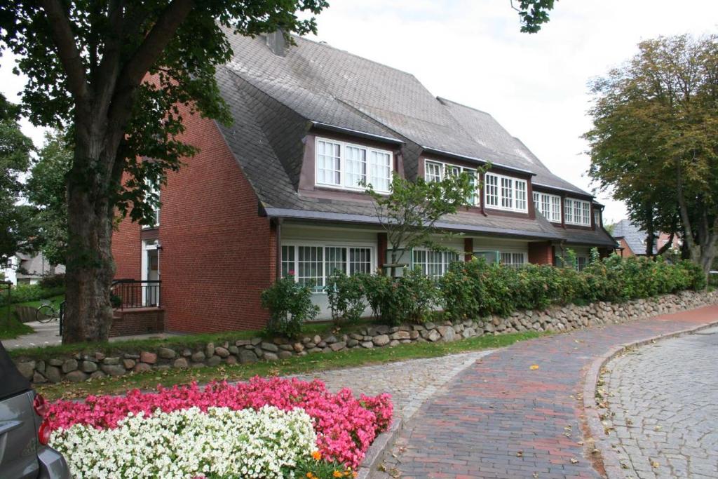 una casa de ladrillo rojo con flores delante en Stadler Kirchenweg en Westerland