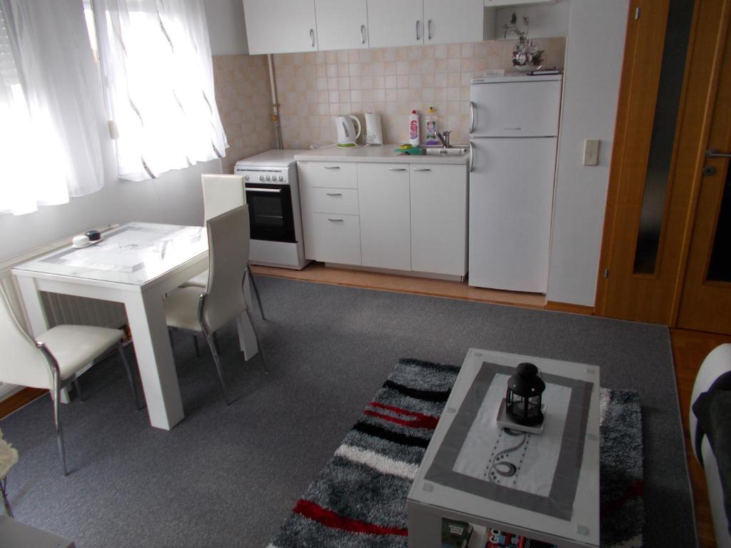 małą kuchnię ze stołem i białą lodówką w obiekcie Albatros A1 w Zagrzebiu