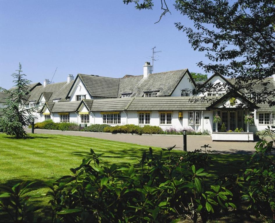 una grande casa bianca con un ampio cortile di Basingstoke Country Hotel & Spa a Hook