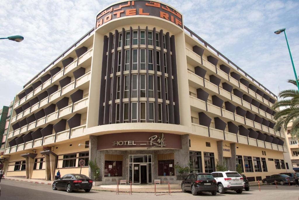Hôtel Rif في مكناس: مبنى كبير فيه سيارات تقف امامه