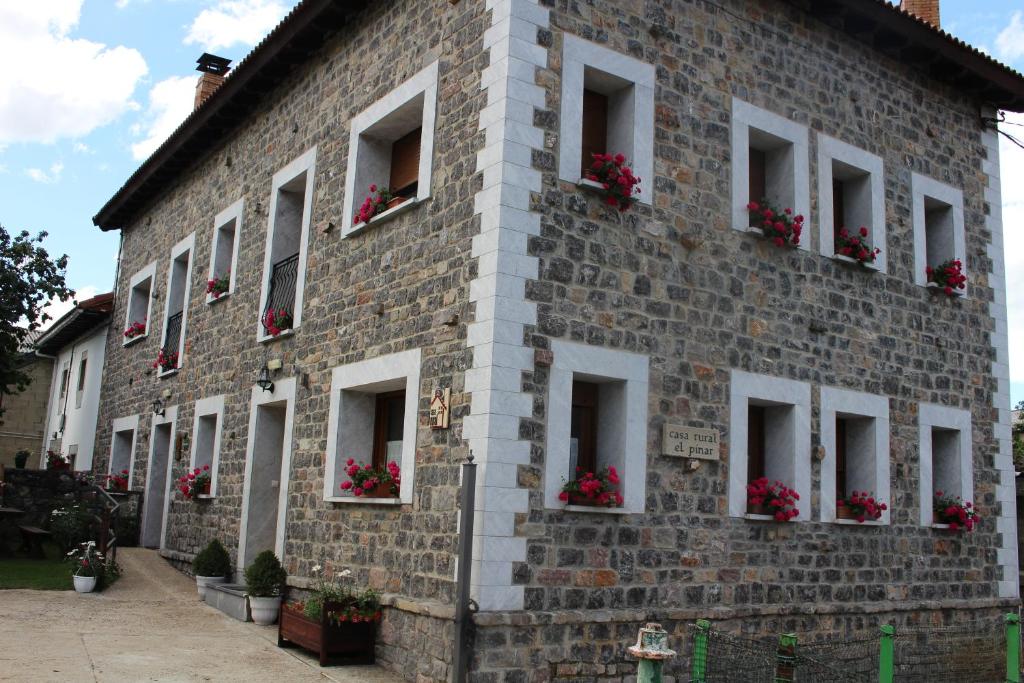 a brick building with flowers in the windows at Casa Rural El Pinar in Acebedo