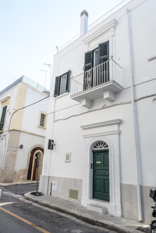 biały budynek z zielonymi drzwiami i balkonem w obiekcie CASA MELIO' w mieście Polignano a Mare