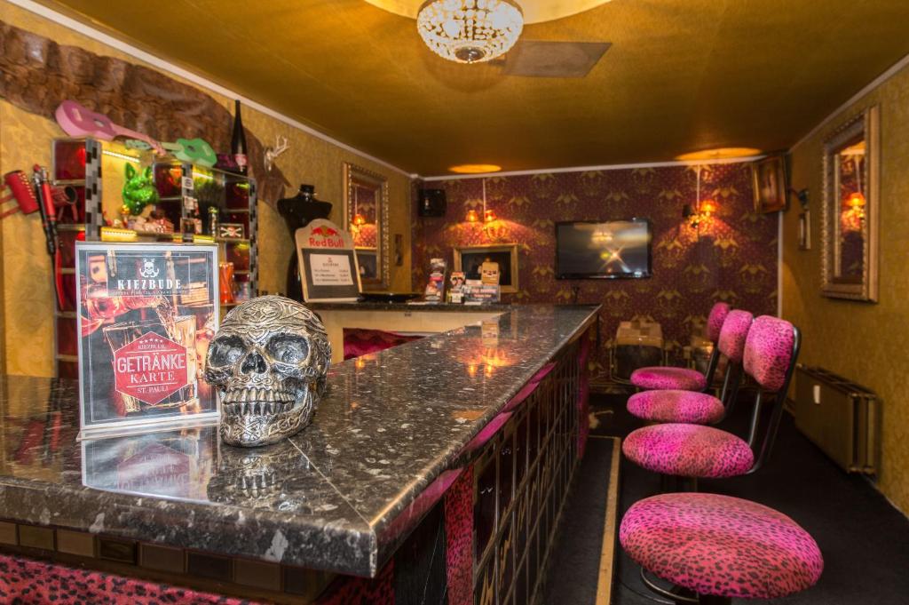 a bar with a skull on the counter and pink stools at Hostel Kiezbude in Hamburg