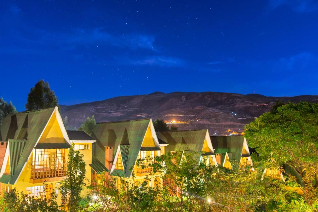 Amaru Valle Hotel في أوروبامبا: صف من البيوت ليلا مع جبل في الخلفية