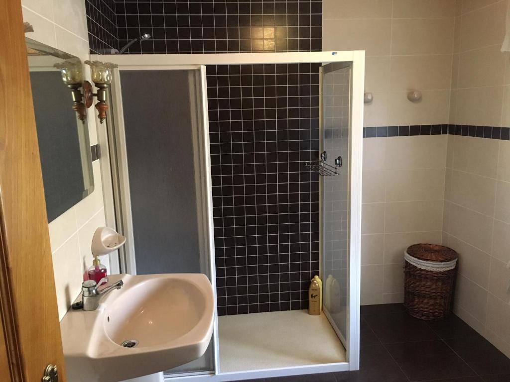 a bathroom with a sink and a shower with black tiles at Vivienda vacacional casa pereira luarca in Cabornas