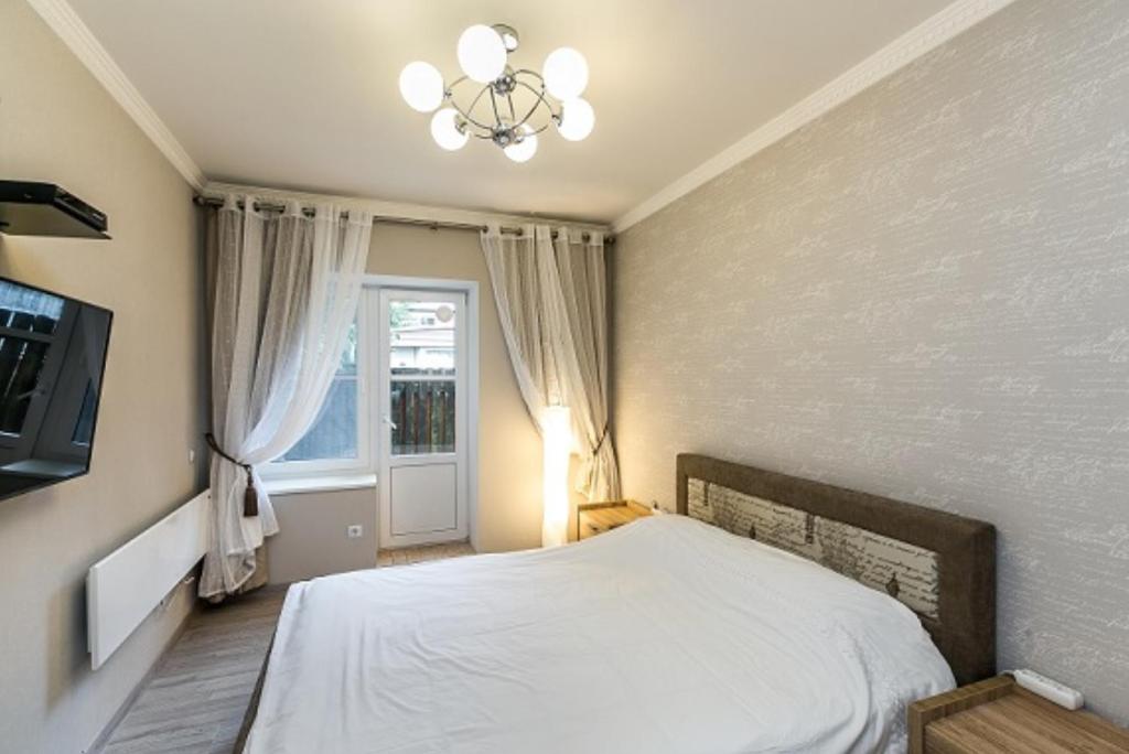 a bedroom with a white bed and a window at Noemi Jurmala Apartment in Jūrmala