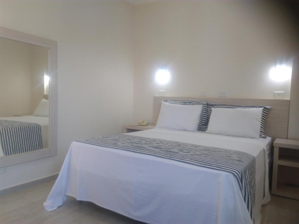 une chambre avec un lit avec des draps blancs et un miroir dans l'établissement Dumont Park Hotel, à Sao Jose do Rio Preto