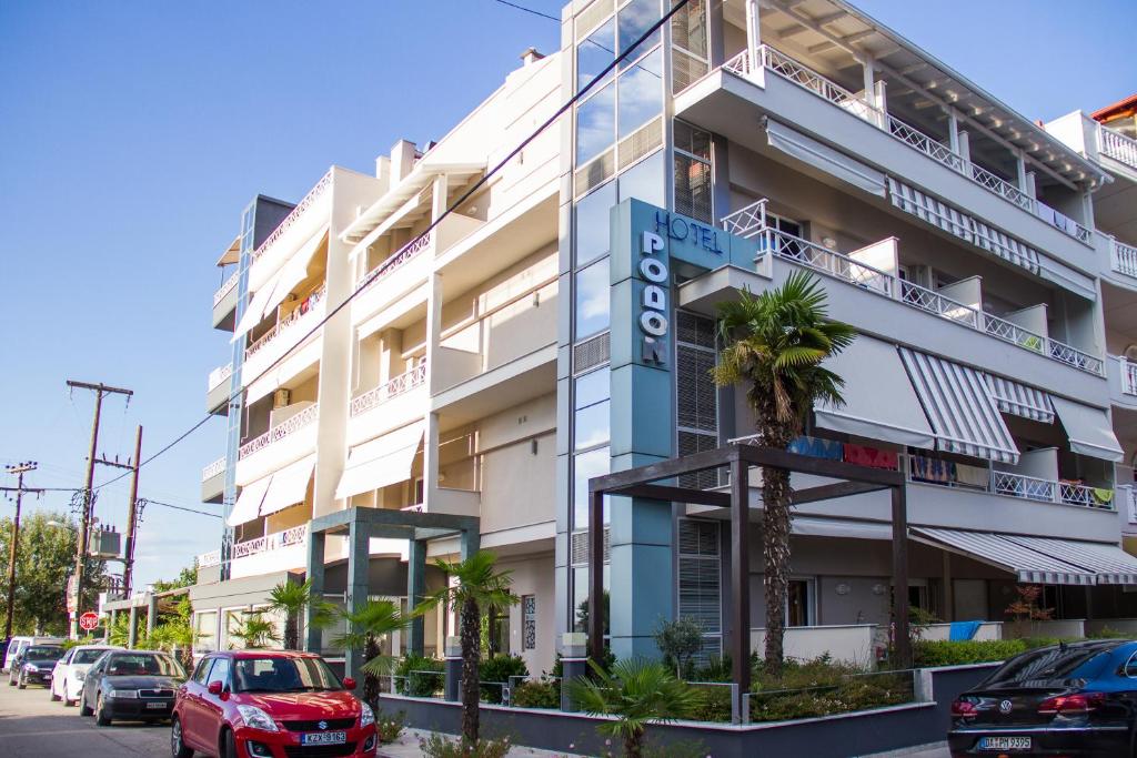 a white building with a blue sign on it at Hotel Rodon in Paralia Katerinis