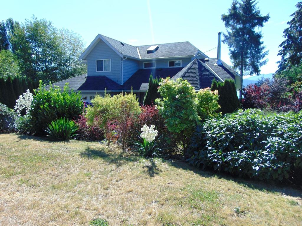 a house with a garden of flowers and bushes at The Oceanfront Inn on Stephens Bay in Coal Harbour