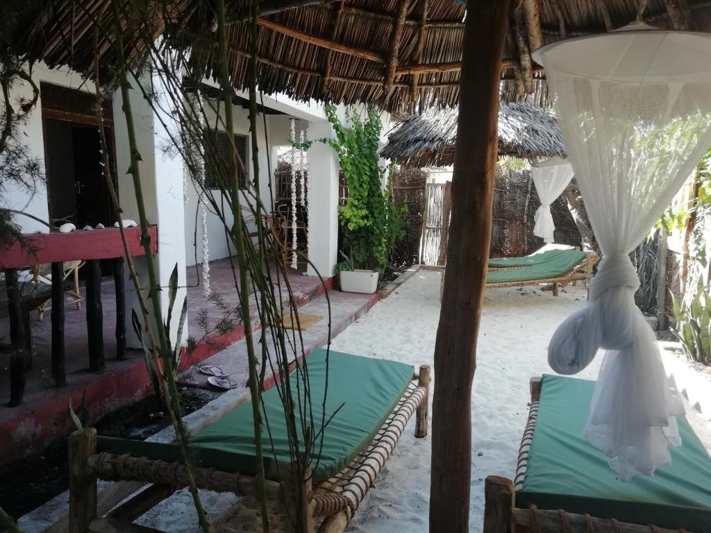 a patio with chairs and umbrellas in a resort at Sunny House Paje II in Paje